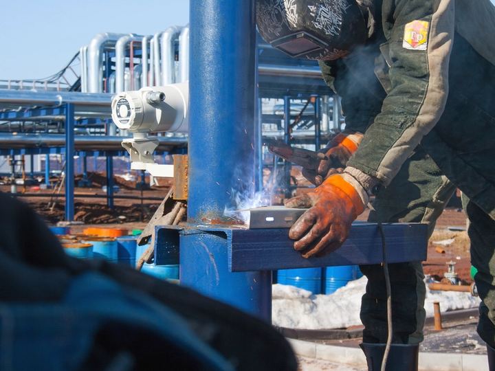 Lasser aan het werk tussen industriële leidingen